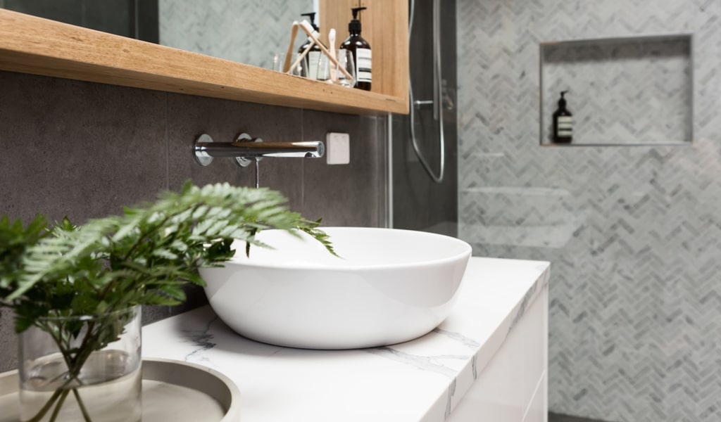 Bathroom vanity unit details with clean white basin with shower tiling behind